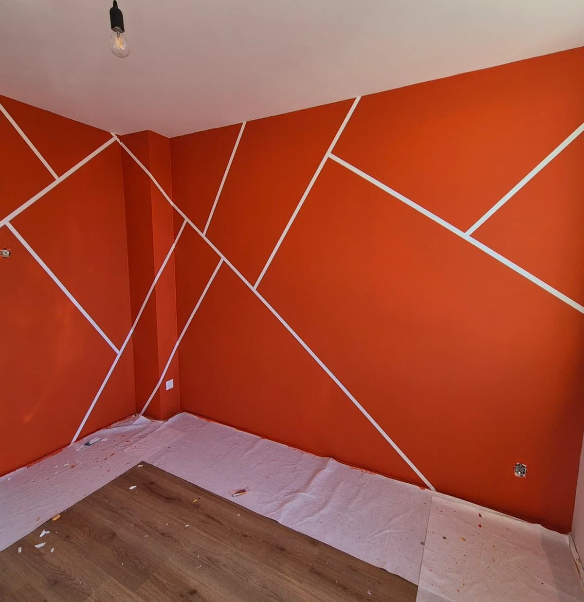 Geometrische accentmuur in oranje tinten, kleuradvies door Schildersbedrijf M. Koster